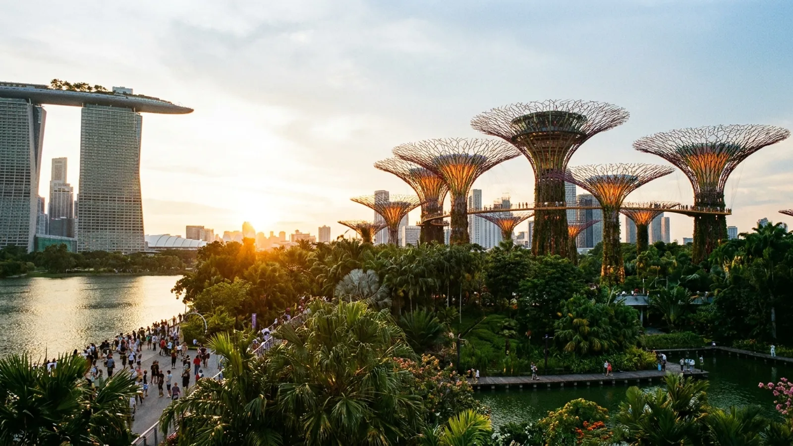 The Supertrees and waterfront at Gardens by the Bay in Singapore at golden hour, with people strolling amid lush greenery