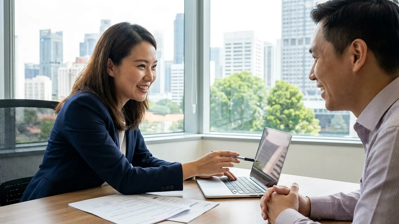 An insurance broker discussing coverage options with a business owner at a desk in Singapore