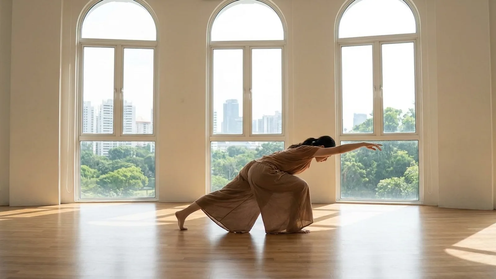 A contemporary dancer mid-movement on the floor in a bright Singapore studio with mirrored walls and natural light