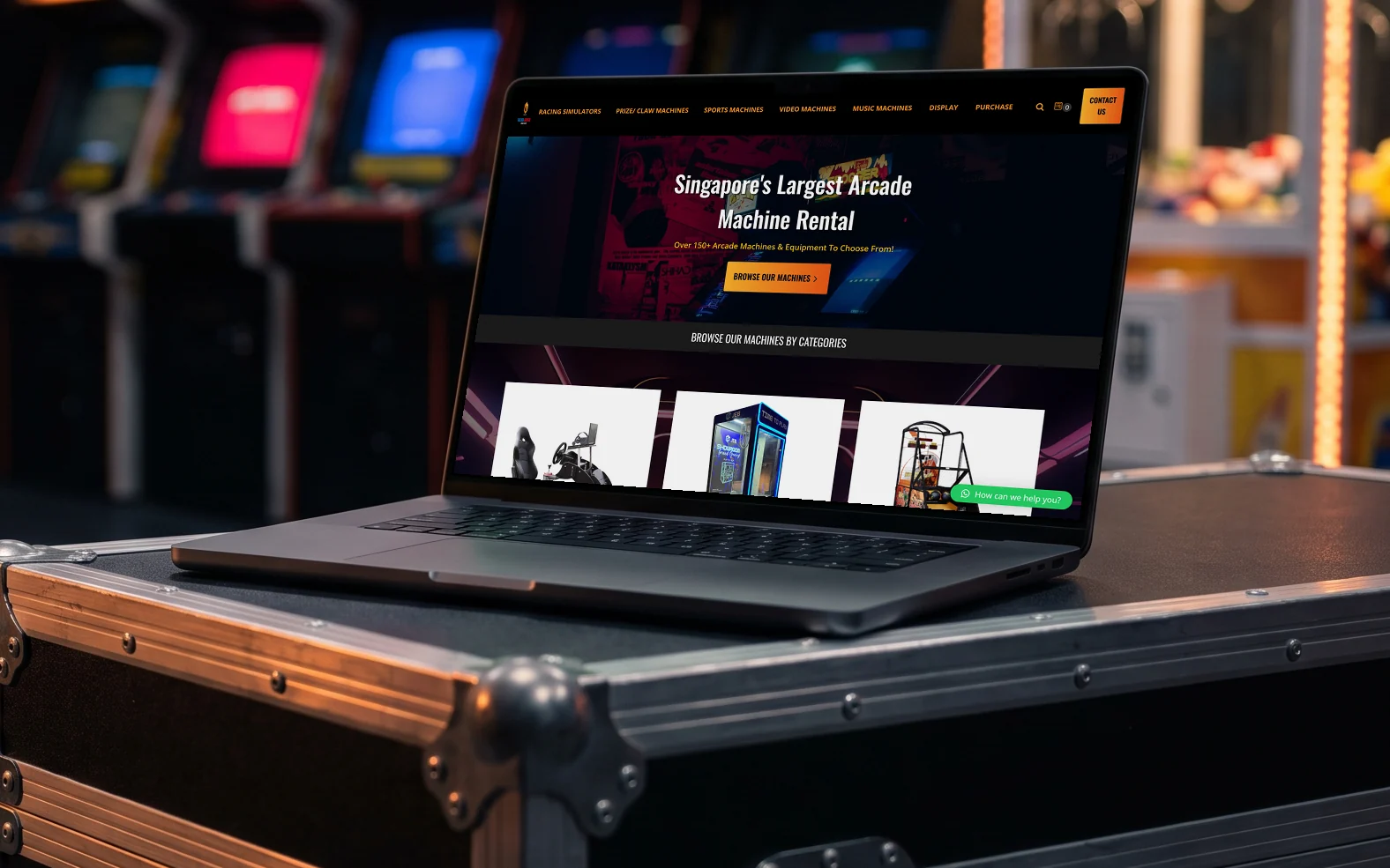 Arcade Rental Singapore homepage, "Singapore's Largest Arcade Machine Rental" above its machine categories, on a laptop resting on a black flight case at an event set-up, arcade cabinets and a claw machine glowing out of focus behind