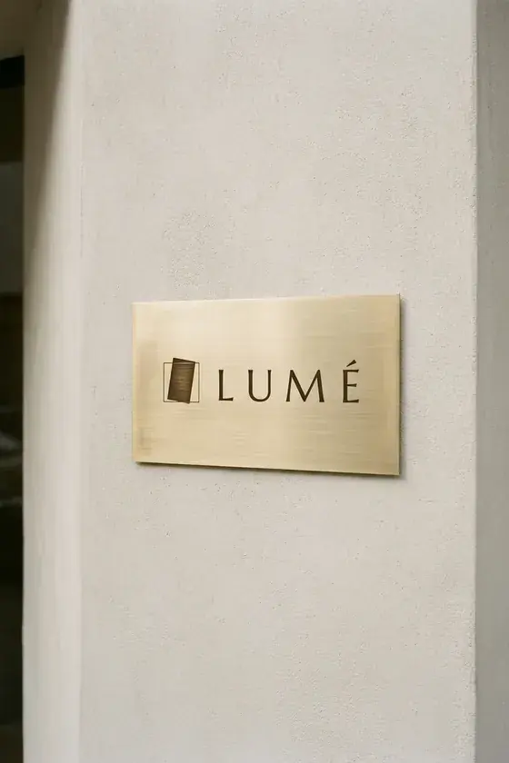 Etched brass Lumé plate mounted flush on a limewash facade