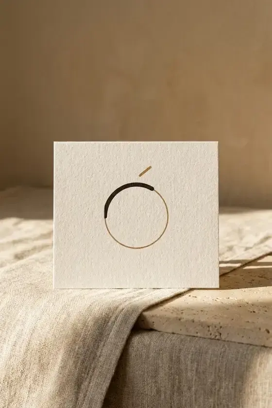Oréa gift card showing the monogram alone, propped on a linen surface