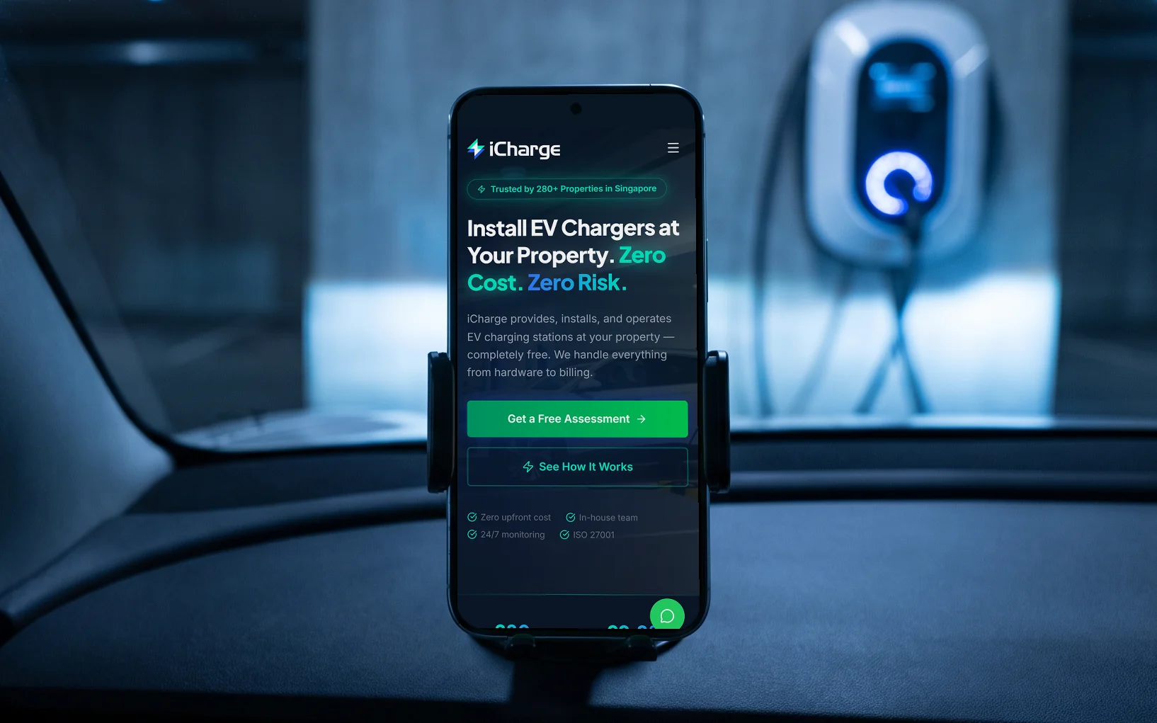 iCharge mobile site, "Install EV Chargers at Your Property. Zero Cost. Zero Risk.", on a phone in a dashboard mount inside an electric car parked at a night-time charging bay