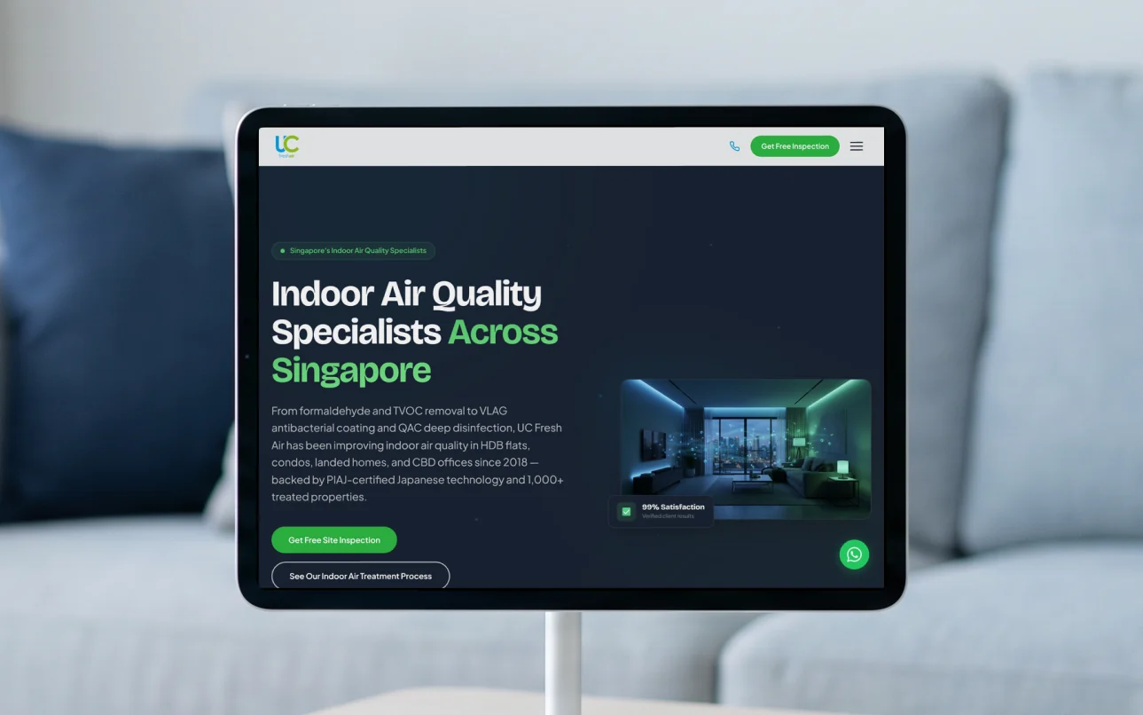 UC Fresh Air homepage, "Indoor Air Quality Specialists Across Singapore" on deep navy, on a tablet on a white stand on a pale ash coffee table in a bright living room with sheer daylit curtains
