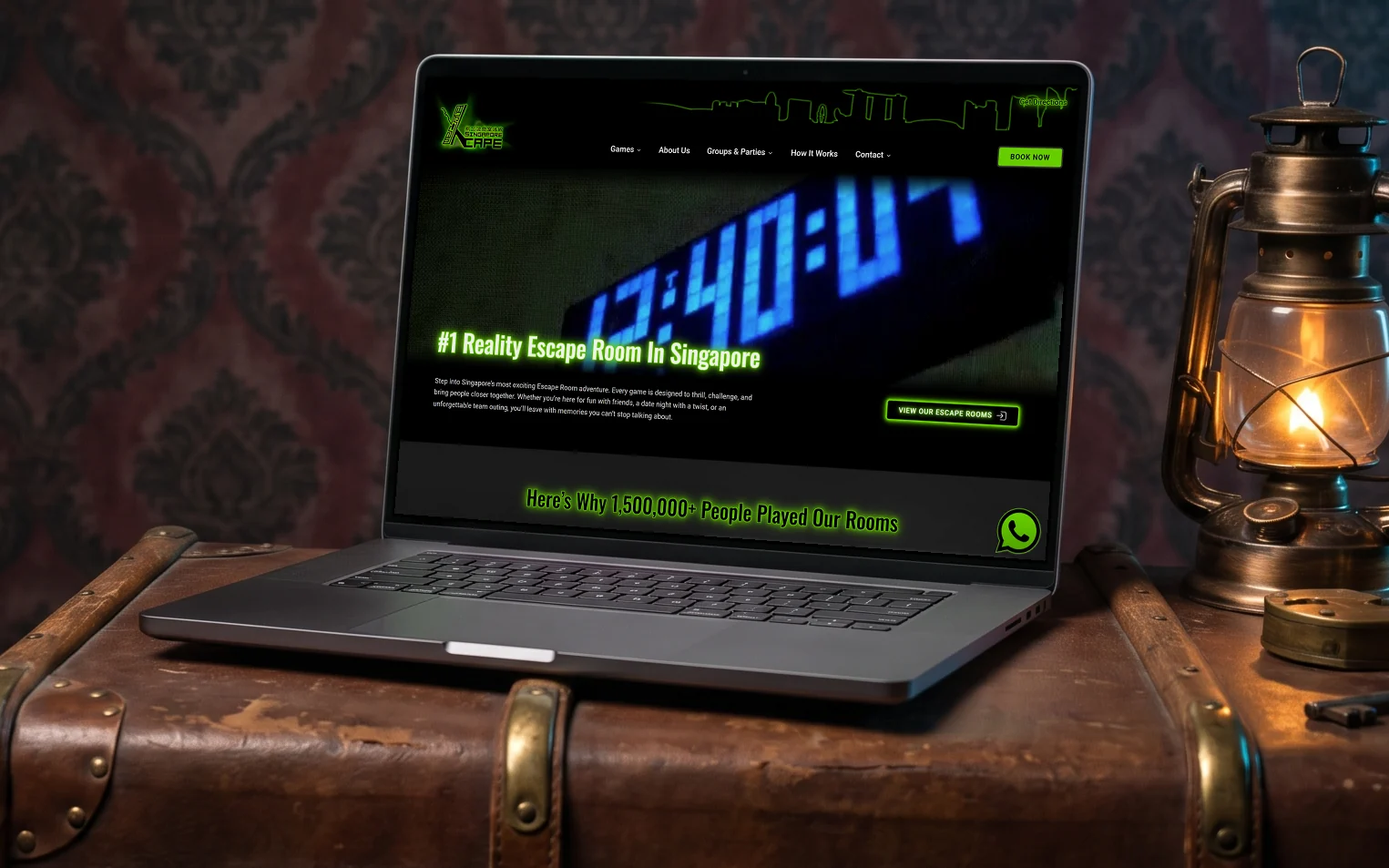 Xcape Singapore homepage, "#1 Reality Escape Room In Singapore" over its blue countdown-timer hero video, on a laptop resting on an antique leather steamer trunk in a dim escape room, lit by an old brass lantern beside two padlocks